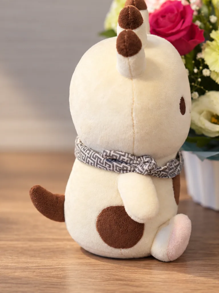 横から見たナンダモンのぬいぐるみ。首巻きの結び目と、短い尻尾が見える。