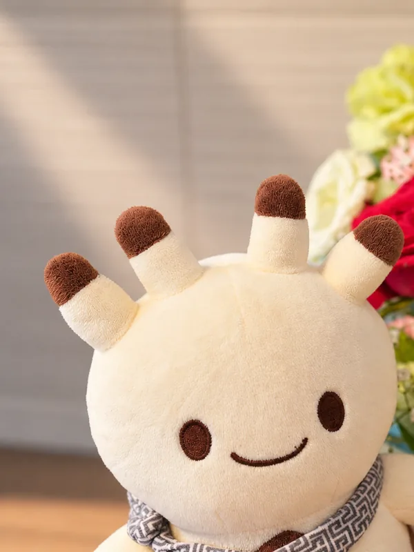 花束の前で、こちらを向いてにっこりするナンダモンのぬいぐるみ。